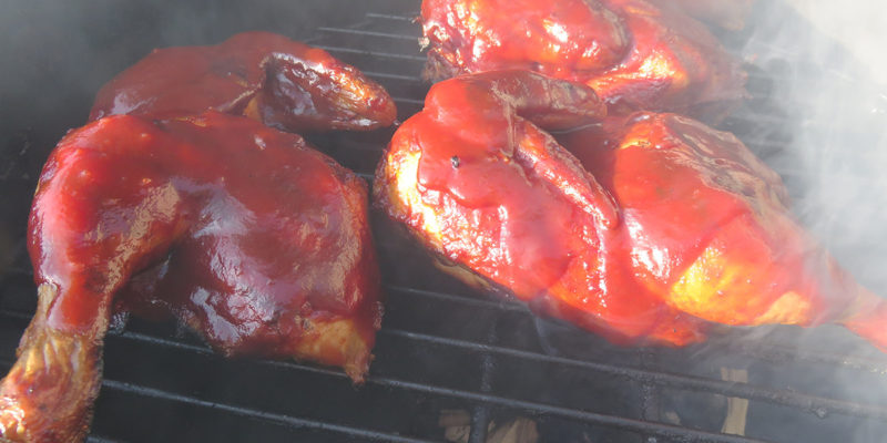 Smoky barbecue chicken cooking on grill